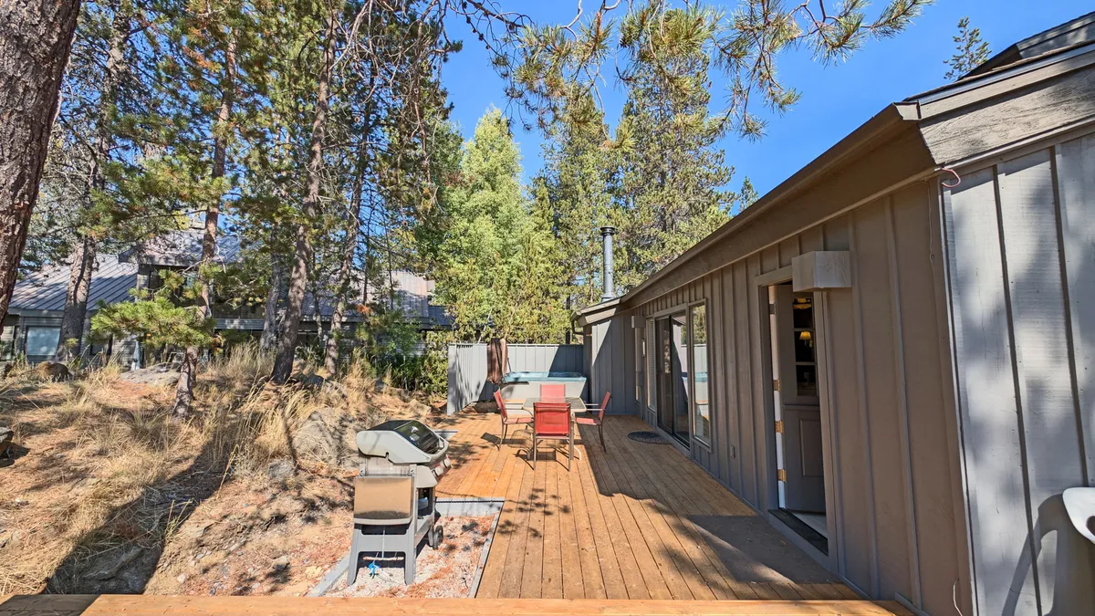 A welcoming wooden deck with an outdoor seating area and grill, ideal for outdoor dining and gatherings. The deck is bathed in sunlight and overlooks natural surroundings, providing the perfect transition from adventure to relaxation.